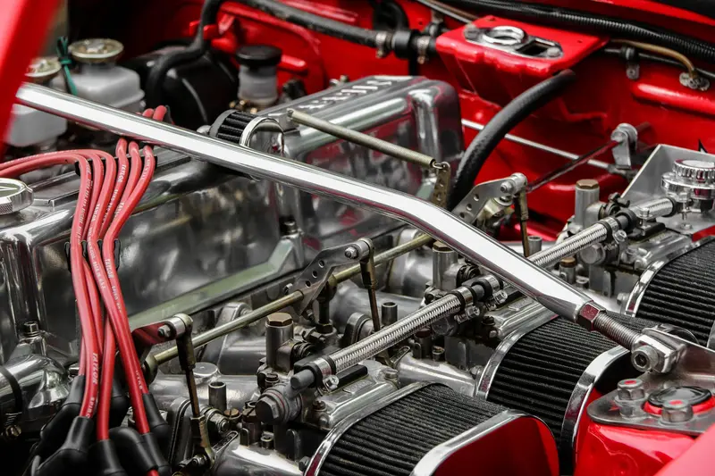 Classic car engine bay with chrome fittings and red ignition leads